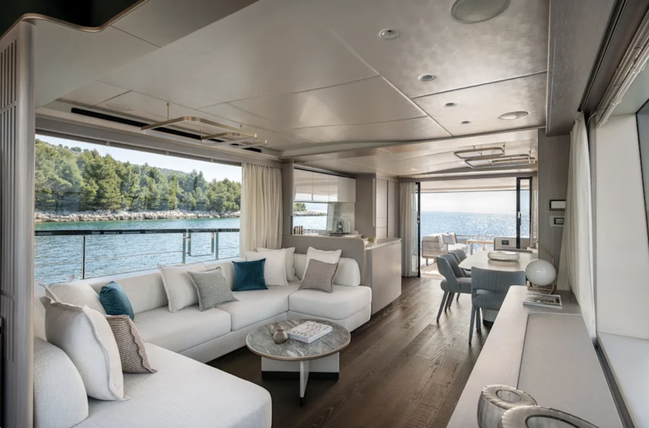 Ljus salong med vinkelsoffa, matplats och panoramafönster mot havet