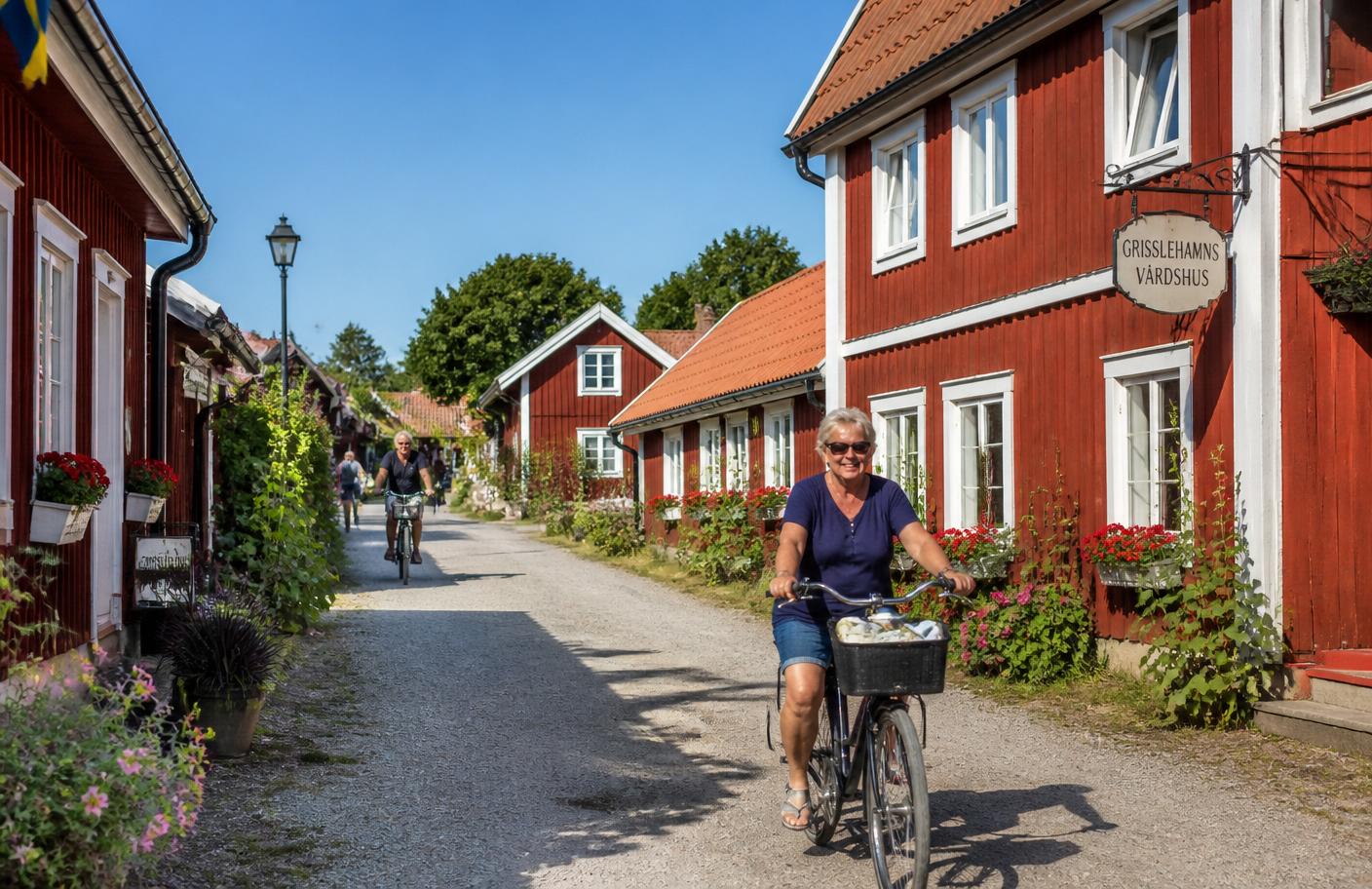 Röda faluröda hus längs bygatan i Grisslehamn en solig sommardag med cyklande människor