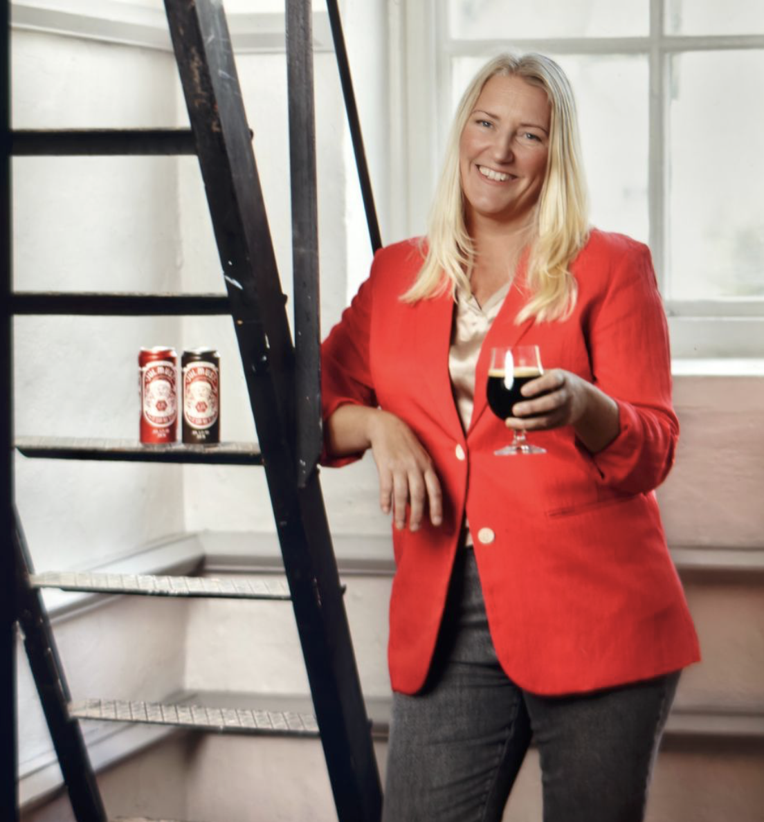 Nina Hagman i röd kavaj med ett glas stark julmust