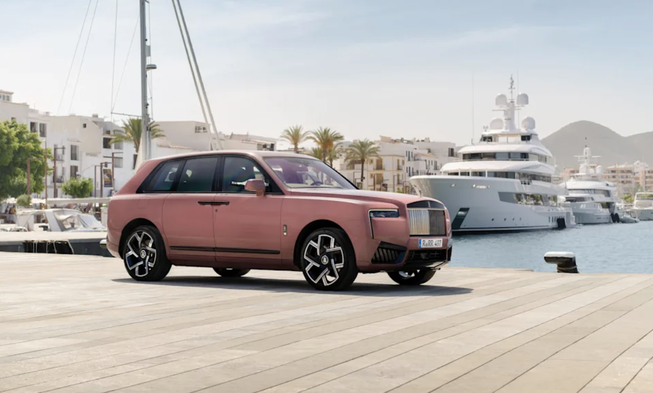 Rolls-Royce Cullinan i rosé-lack vid kaj med superyacht i bakgrunden