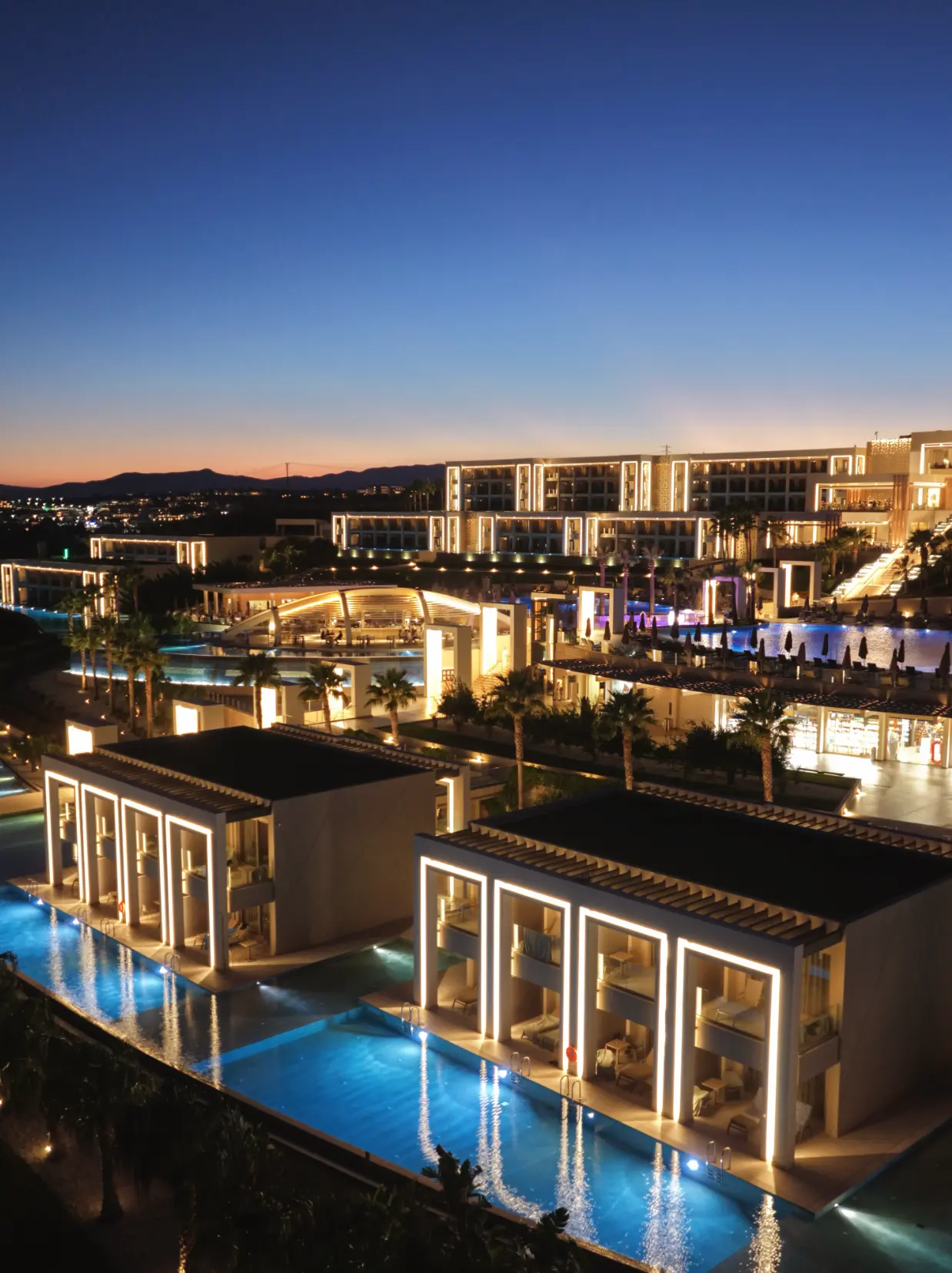 Mayia Exclusive Resort & Spa upplyst i skymningen med pooler och palmer