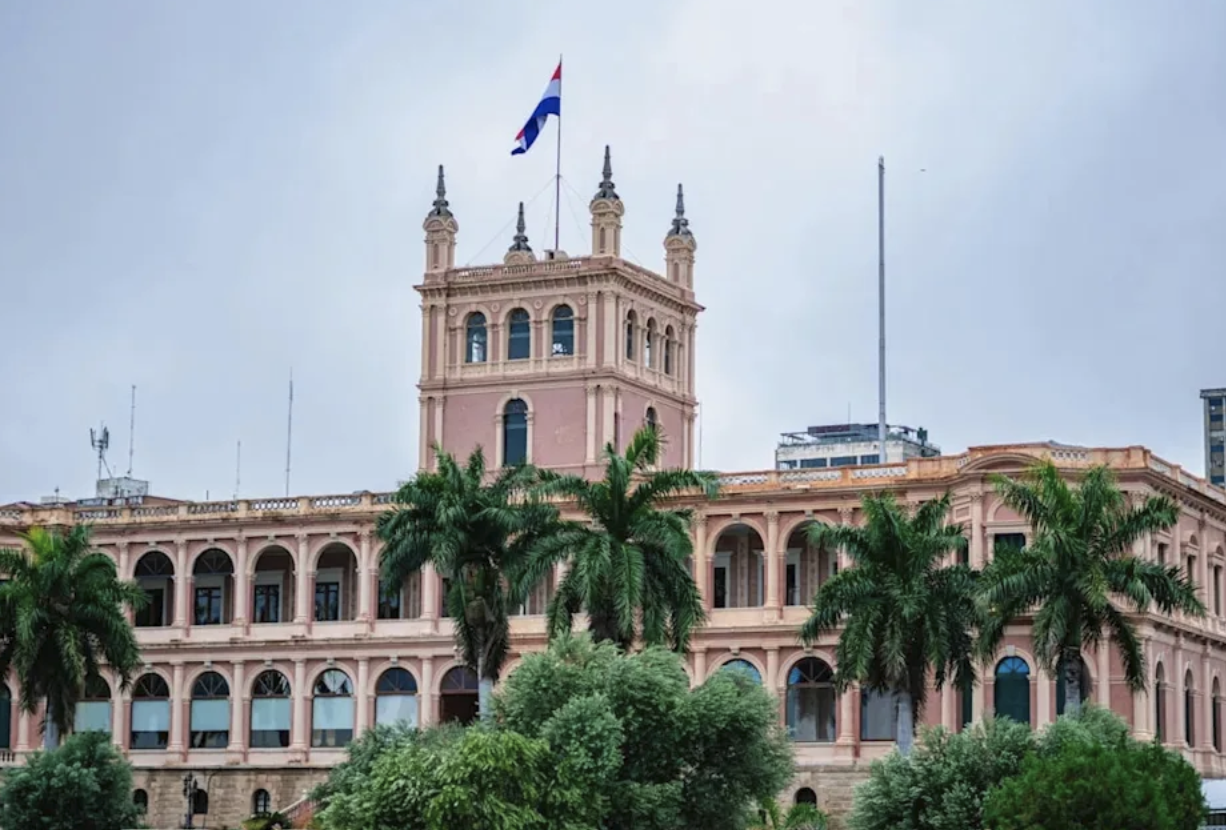 Det rosa presidentpalatset i Asunción med Paraguays flagga och palmer framför