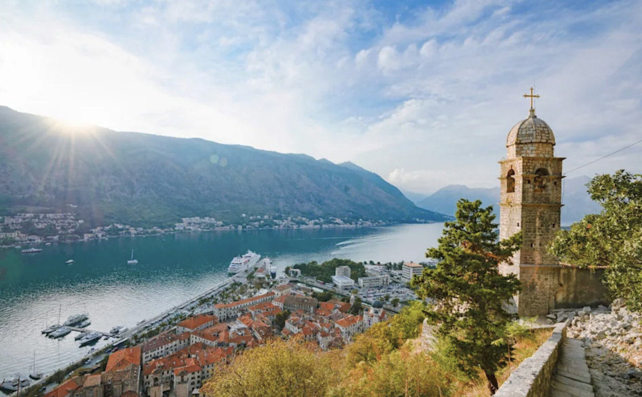 Kotorbukten i Montenegro med kyrktorn i förgrunden, berg och kryssningsfartyg i hamnen