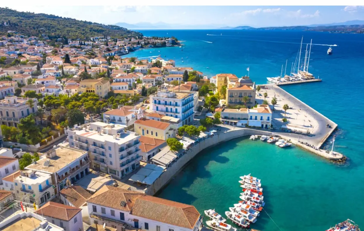 Flygbild över hamnen på den grekiska ön Spetses med båtar och vita hus