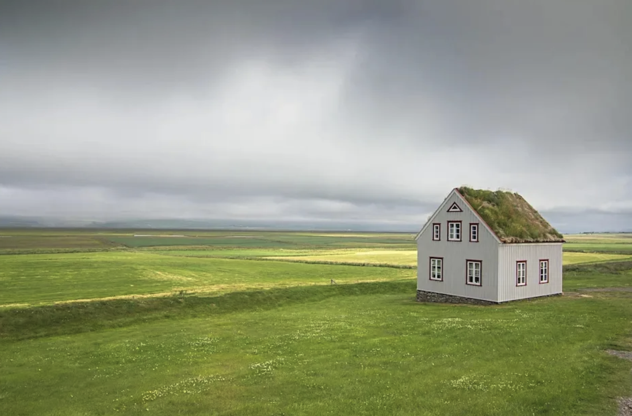 Traditionellt islandskt torvtakshus i ett öppet grönt landskap
